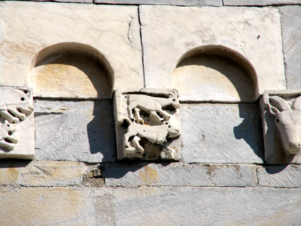 Stazzema (Lucca), chiesa di S. Maria Assunta, facciata: teoria di archetti pensili con mensole figurate, particolare. Stazzema (Lucca), chiesa di S. Maria Assunta, facciata: teoria di archetti pensili con mensole figurate, particolare.